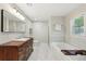 Bright bathroom featuring a wooden vanity, modern fixtures, and a separate soaking tub with beautiful tile work at 3302 W Beaumont St, Tampa, FL 33611