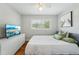 Cozy bedroom with a comfortable bed, modern TV, dresser, ceiling fan and ample natural light from the window at 3302 W Beaumont St, Tampa, FL 33611