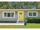 Close up view of the yellow front door of the home, flanked by windows and greenery at 3302 W Beaumont St, Tampa, FL 33611