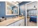 Bathroom with blue walls, white vanity, large mirror, and doorway into bedroom at 3938 Lake Joyce Dr, Land O Lakes, FL 34639