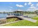 Picturesque covered boat dock on the water with lounge chairs and boat lift at 3938 Lake Joyce Dr, Land O Lakes, FL 34639