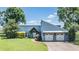 Stunning blue home featuring a well manicured lawn, attractive landscaping, and a two car garage at 3938 Lake Joyce Dr, Land O Lakes, FL 34639