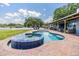 Backyard oasis featuring a pool, spa, patio, and covered patio with lake view at 3938 Lake Joyce Dr, Land O Lakes, FL 34639