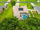 Aerial view highlighting the home's screened pool, roof, solar paneling, and surrounding landscaping at 4615 Cozzo Dr, Land O Lakes, FL 34639