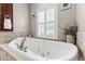 Well-lit bathroom featuring a luxurious soaking tub with shuttered window and decorative accents at 4615 Cozzo Dr, Land O Lakes, FL 34639