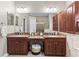 Bathroom featuring a double vanity with granite countertop, dark wood cabinets and framed mirror at 4615 Cozzo Dr, Land O Lakes, FL 34639