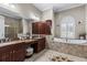 Bathroom with dual sinks, granite counters, dark wood cabinets and a garden tub at 4615 Cozzo Dr, Land O Lakes, FL 34639