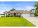 Beautiful single-story home featuring a well-manicured lawn, tropical landscaping, and a three-car garage at 4615 Cozzo Dr, Land O Lakes, FL 34639