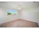 Bright bedroom featuring wood-look floors, ceiling fan, and a window with a view of palm trees at 5647 110Th Way, Seminole, FL 33772
