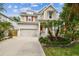 Inviting two-story home with lush landscaping, covered porch, American flag, and a two-car garage at 6022 S Elkins Ave, Tampa, FL 33611