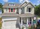 Charming two-story home with a welcoming front porch, colorful American flags, and a two car garage at 6022 S Elkins Ave, Tampa, FL 33611