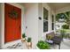 Charming front porch with a red door, a wreath, a bench, and plants at 6022 S Elkins Ave, Tampa, FL 33611
