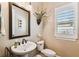 Half bath featuring a pedestal sink, decorative mirror, window with blinds, and modern fixtures at 6022 S Elkins Ave, Tampa, FL 33611