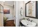 Stylish powder room featuring a vessel sink, dark fixtures, framed mirror, and wood-look flooring at 6022 S Elkins Ave, Tampa, FL 33611