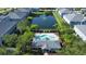 Aerial view showcasing a community pool, clubhouse, and beautiful pond with fountain surrounded by lush landscaping at 6304 Parkside Meadow Dr, Tampa, FL 33625