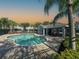 Community pool with a covered seating area, lounge chairs, palm trees, and a brick paver deck at 6304 Parkside Meadow Dr, Tampa, FL 33625