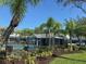 Community pool area with black fence, palm trees, lounge chairs, and well-maintained landscaping for relaxation at 6304 Parkside Meadow Dr, Tampa, FL 33625