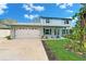 Traditional light blue two-story home with a white garage and a well-maintained front lawn at 9410 Alanbrooke St, Temple Terrace, FL 33637