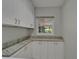 Bright laundry room features white cabinets, granite countertops, stainless steel appliances, and natural light at 9410 Alanbrooke St, Temple Terrace, FL 33637