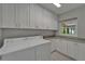 Bright laundry room features white cabinets, granite countertops, stainless steel appliances, and natural light at 9410 Alanbrooke St, Temple Terrace, FL 33637