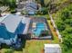 Aerial view of a screened pool and spa with a well-maintained lawn and manicured landscaping at 9410 Alanbrooke St, Temple Terrace, FL 33637