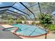 Screened-in pool area with a hot tub and lush tropical landscaping at 9410 Alanbrooke St, Temple Terrace, FL 33637