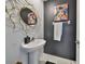 Stylish powder room with pedestal sink, designer mirror, and vibrant artwork creating a modern aesthetic at 9914 Calypso Orchid Ct, Riverview, FL 33578