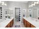 Dual vanity bathroom with wood cabinets, mirrors, and tile flooring at 2207 Climbing Ivy Dr, Tampa, FL 33618