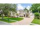 The home has an inviting brick driveway with palm trees and lush landscaping framing its stately facade at 2207 Climbing Ivy Dr, Tampa, FL 33618