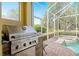 Screened-in lanai features a built-in KitchenAid grill, brick pavers, and a refreshing pool with integrated jacuzzi at 2207 Climbing Ivy Dr, Tampa, FL 33618