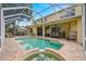 The screened-in lanai features a pool, hot tub, and covered seating area with a table, chairs, and ceiling fans at 2207 Climbing Ivy Dr, Tampa, FL 33618