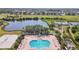 Aerial view of a large community pool area with lounge chairs, tennis courts, and a lake in the background at 1003 Fairwaycove Ln # 103, Bradenton, FL 34212