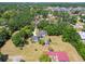 Aerial view of a property with mature trees, green lawn, and a quaint home at 101 N Taylor Rd, Seffner, FL 33584