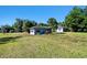 Exterior view of cozy blue house and additional building surrounded by expansive lawn and mature trees at 101 N Taylor Rd, Seffner, FL 33584