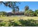 Backyard view of a screened-in pool with palm trees and vegetation at 101 N Taylor Rd, Seffner, FL 33584