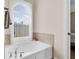 Bathroom with an arched window and a luxurious soaking tub with elegant fixtures and travertine tile surround at 10911 Rockledge View Dr, Riverview, FL 33579