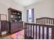 Well-lit bedroom with a crib, dark wood dresser, window, wood-look floors and a colorful rug at 10911 Rockledge View Dr, Riverview, FL 33579