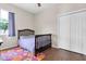 Cozy bedroom featuring a crib, closet, window, wood-look floors and a colorful rug at 10911 Rockledge View Dr, Riverview, FL 33579