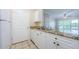 Efficient kitchen with stainless steel sink, granite counters, white cabinets and appliances next to doorway at 1216 S Missouri Ave # 108, Clearwater, FL 33756