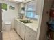 Functional kitchen with white appliances, cabinetry, a green sink and tile flooring at 1301 S Hercules Ave # 19, Clearwater, FL 33764