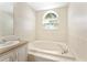 Bright bathroom featuring a soaking tub under an arched window letting in natural light at 14506 Alejo Ct, Seminole, FL 33776