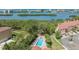 Aerial view of a private swimming pool and hot tub surrounded by trees, lush tropical greenery, and a bay view at 14506 Alejo Ct, Seminole, FL 33776
