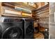Modern laundry room with wood walls, matching black washer and dryer, and stylish storage cabinets at 146 8Th Ne Ave, St Petersburg, FL 33701