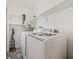 Modern laundry room with updated washer and dryer, complemented by stylish black and white patterned tile flooring at 1577 Chateaux De Ville Ct, Clearwater, FL 33764