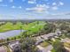 Scenic aerial view of a golf course community with lush landscaping, a pond and a skyline in the background at 1714 Cypress Ave, Belleair, FL 33756