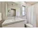 Clean bathroom features a single vanity with large mirror, toilet and a shower with white tile and a shower curtain at 1714 Cypress Ave, Belleair, FL 33756