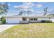 Charming one-story home with a well-manicured lawn, attached garage, and welcoming entrance at 1714 Cypress Ave, Belleair, FL 33756