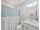 Bright bathroom featuring a white vanity, toilet, and a shower with a blue and white curtain at 17737 Everlong Dr, Land O Lakes, FL 34638