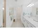 Bright bathroom featuring a double sink vanity with white cabinets, elegant fixtures and a glass enclosed shower at 17737 Everlong Dr, Land O Lakes, FL 34638