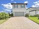 Charming two-story home featuring a gray two-car garage, complemented by a beautifully paved driveway and manicured front yard at 17737 Everlong Dr, Land O Lakes, FL 34638